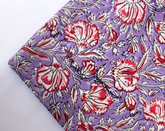 May include: Purple fabric with a floral print featuring white and pink flowers with black outlines.