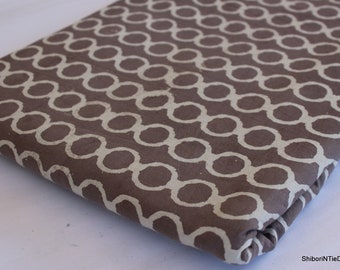 May include: Brown fabric with a white geometric pattern of circles. The fabric is folded and the pattern is visible on both sides.