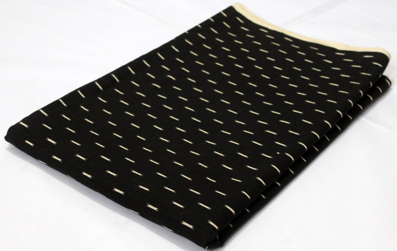 May include: Black fabric with a white dotted pattern. The fabric is folded in half and the edges are visible.