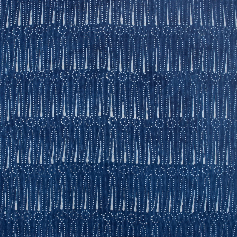 May include: A blue fabric with a white pattern of small circles and vertical lines. The pattern is repeated throughout the fabric.