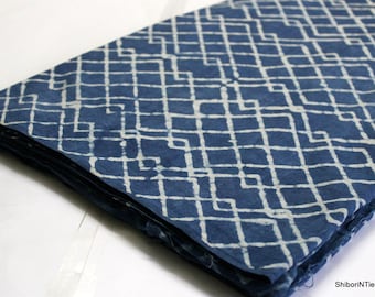 May include: A folded piece of indigo blue fabric with a white geometric pattern. The fabric is folded in a triangular shape and has a white background.