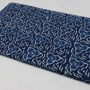 May include: A folded piece of blue and white fabric with a geometric pattern. The fabric is made of cotton and has a soft, natural feel.