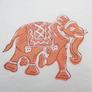 May include: A hand-painted orange elephant with white details on a white background. The elephant is decorated with a patterned saddle and has a curled trunk.
