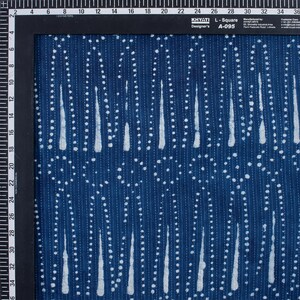 May include: A blue fabric with a white pattern of dots and vertical lines. The fabric has a textured surface and is made of cotton. The fabric is labelled "KHYATI Designer's L-Square A-095".