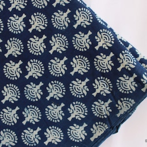 May include: Indigo blue cotton fabric with a white floral pattern. The fabric is folded in half and the pattern is visible on both sides.