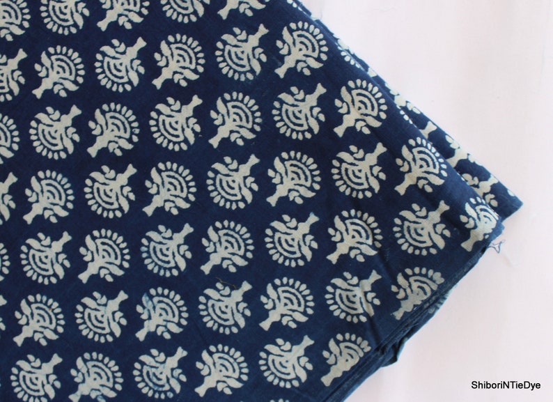May include: Indigo blue cotton fabric with a white floral pattern. The fabric is folded in half and the pattern is visible on both sides.