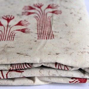 May include: A folded piece of fabric with a white background and a red floral pattern. The fabric is folded in thirds and the edges are visible.