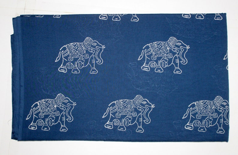 May include: Blue cotton fabric with a white elephant print. The elephants are in a traditional Indian style with intricate details.