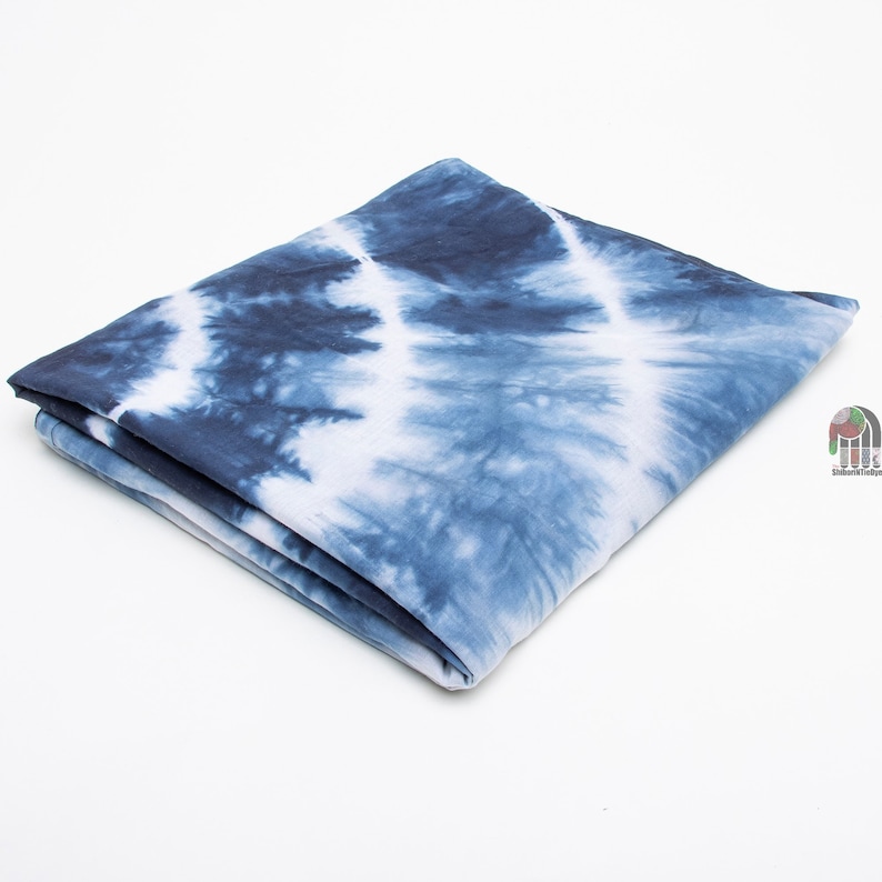 May include: A folded blue and white tie-dye fabric with a swirling pattern.