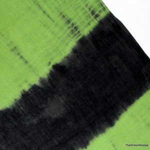 Op de afbeelding: Een groene en zwarte tie-dye stof met een verloop patroon. De stof is gemaakt van een zacht, lichtgewicht materiaal en heeft een gladde textuur.