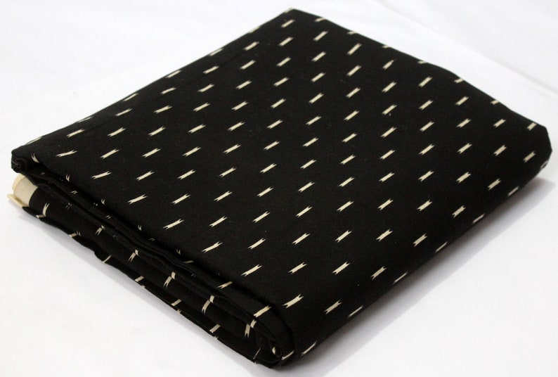May include: Black fabric with a white geometric pattern. The fabric is folded in half and the pattern is visible on both sides.