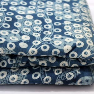 May include: A folded piece of blue fabric with a white pattern of circles and leaves. The fabric is a cotton blend and has a soft, natural feel.