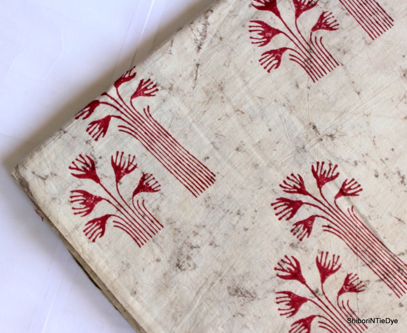 May include: White cotton fabric with a red floral print. The fabric has a rustic, hand-dyed look.