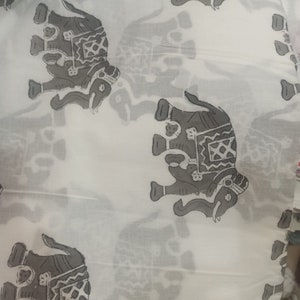 May include: White fabric with a repeating pattern of gray elephants. The elephants are stylized and have intricate designs on their bodies.