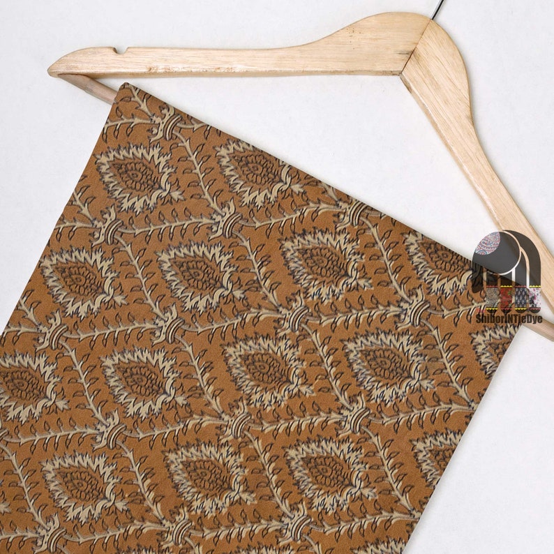 May include: A brown fabric with a beige and black floral pattern. The fabric is draped over a wooden hanger.