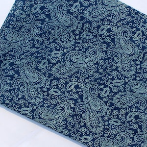 May include: A dark blue fabric with a white paisley pattern. The fabric is soft and has a smooth texture.