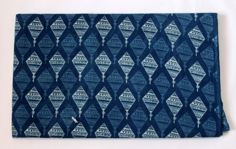 May include: A blue fabric with a white patterned design of kites. The fabric has a subtle texture and a slightly faded look.