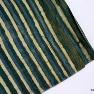 May include: A close-up of a fabric with a striped pattern in shades of green, blue, and cream. The fabric is folded, showing the texture and colour variations. The ShiboriNTieDye logo is in the bottom right corner.