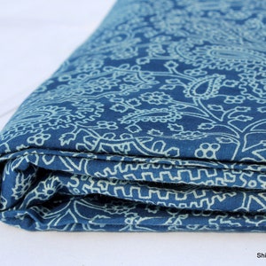 May include: A folded blue fabric with a white paisley pattern. The fabric is soft and has a subtle sheen.