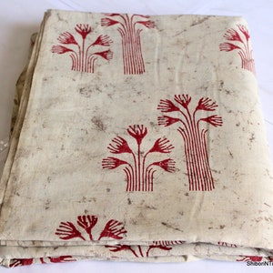 May include: A folded piece of fabric with a white background and a red floral pattern. The fabric has a rustic, vintage look.