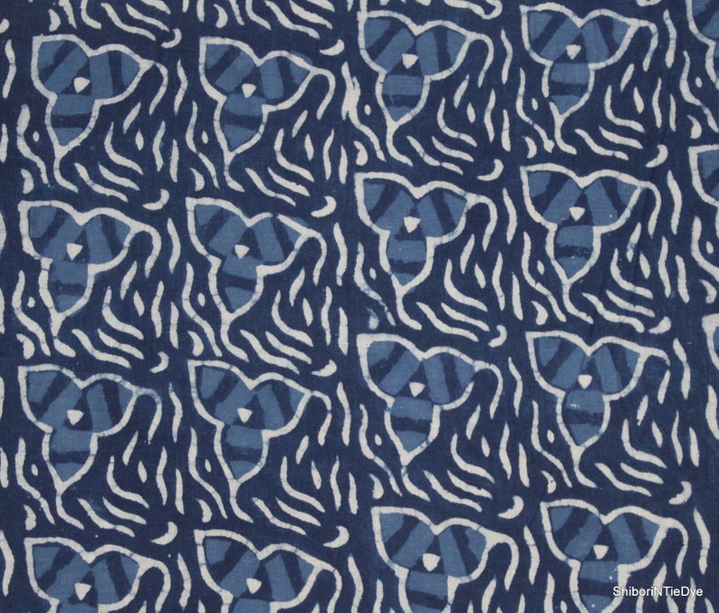May include: Indigo blue fabric with a white pattern of repeating three-leaf clover shapes and wavy lines. The fabric has a hand-dyed, tie-dye look.