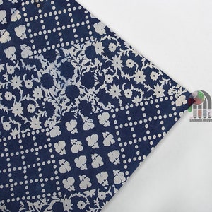 May include: A blue and white fabric with a floral and polka dot pattern. The fabric is made using a shibori tie dye technique.