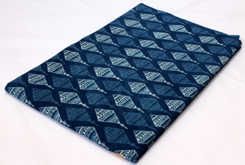 May include: A blue cotton fabric with a white diamond pattern. The fabric has a traditional Indian design.