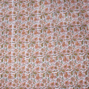 May include: White fabric with a repeating pattern of small orange and green flowers.