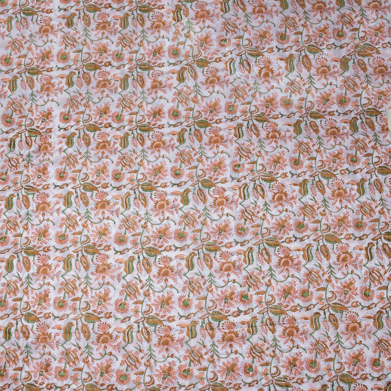 May include: White fabric with a repeating pattern of small orange and green flowers.