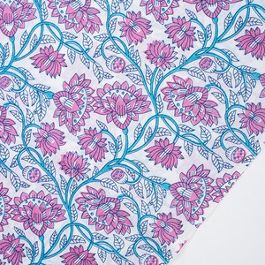 May include: A white fabric with a pink and blue floral pattern. The pattern features stylised flowers and leaves.