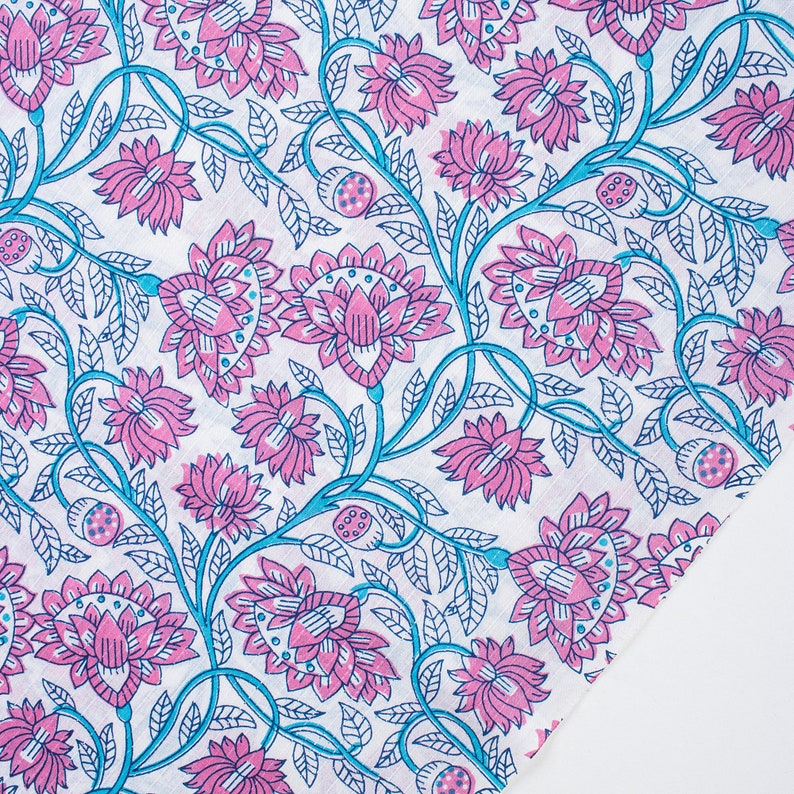 May include: A white fabric with a pink and blue floral pattern. The pattern features stylised flowers and leaves.