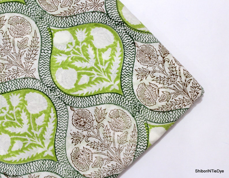 May include: Green and brown floral fabric with a white background. The fabric has a repeating pattern of stylised flowers and leaves.