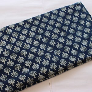 May include: A folded piece of blue fabric with a white floral pattern. The fabric is folded in half and the pattern is visible on both sides.