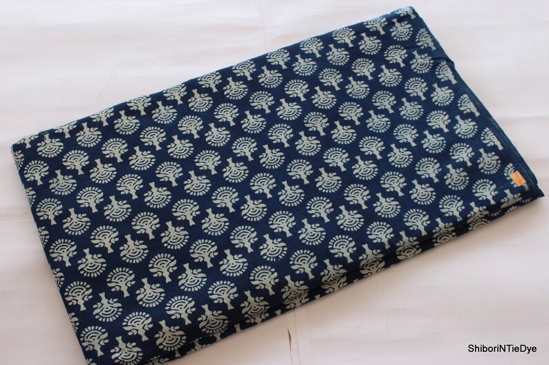 May include: A folded piece of blue fabric with a white floral pattern. The fabric is folded in half and the pattern is visible on both sides.