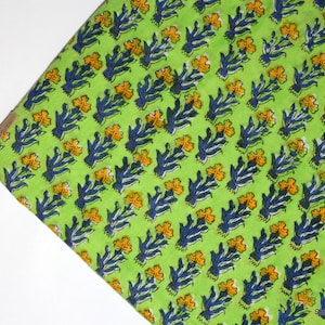 以下が含まれることがあります： 青と黄色の花柄が繰り返し描かれた緑色の布。布は薄い緑色で、微妙な質感がある。