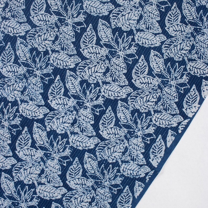 May include: Blue fabric with a white leaf pattern. The fabric has a textured surface.