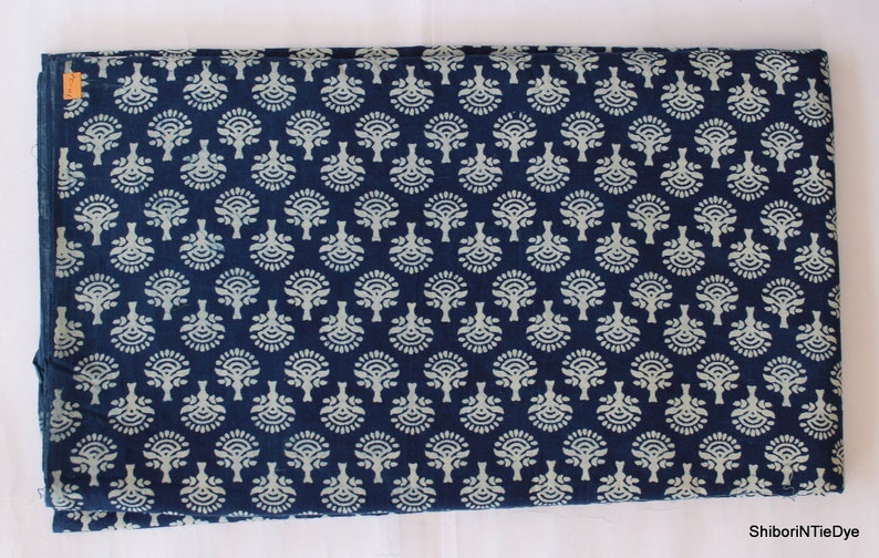 May include: Indigo blue cotton fabric with a white floral pattern. The fabric is folded in half and has a small tag on the top left corner.
