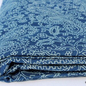May include: A folded piece of blue fabric with a white paisley pattern. The fabric is folded in thirds and the edges are visible.