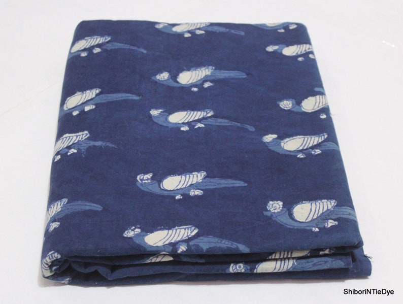 K&ouml;nnte beinhalten: Ein gefaltetes St&uuml;ck indigo-blauer Baumwollstoff mit einem wei&szlig;en Vogelmuster. Der Stoff ist ein traditionelles indisches Handblockdruckdesign.