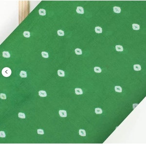 May include: Green fabric with a white polka dot pattern. The fabric has a subtle sheen and a soft texture.