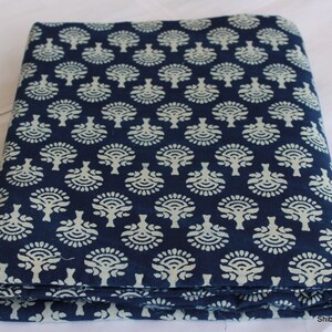 May include: A folded piece of indigo blue cotton fabric with a white floral pattern. The fabric is printed with a repeating design of stylized trees.