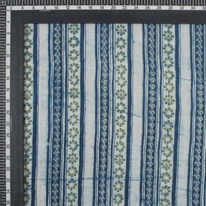May include: Close-up of a fabric with a repeating pattern of vertical stripes in navy blue and white. The stripes are interspersed with rows of small green floral designs. The fabric is likely cotton or linen.