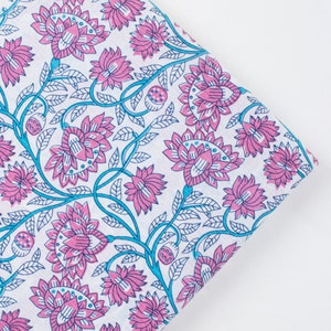 May include: White fabric with a pink and blue floral pattern. The fabric features a repeating design of stylised flowers with intricate details.