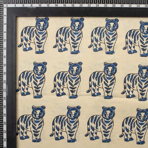 May include: A repeating pattern of blue and white tigers. The tigers are stylized with blue stripes and details, set against a cream-colored background. The image is framed with a black border and includes a ruler along the side.