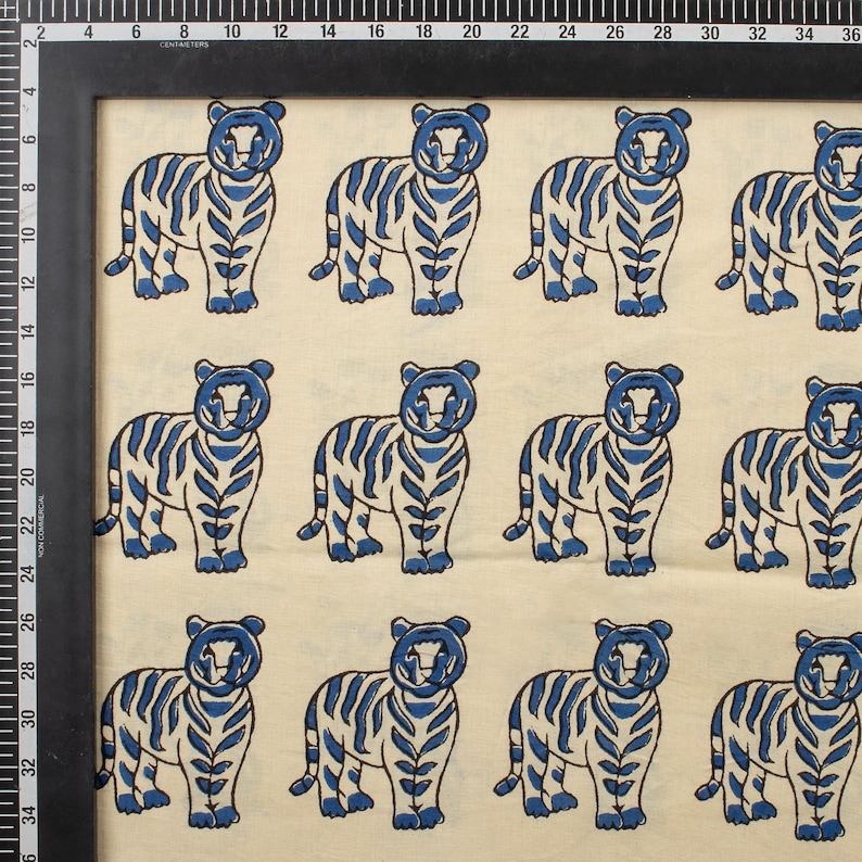 May include: A repeating pattern of blue and white tigers. The tigers are stylized with blue stripes and details, set against a cream-colored background. The image is framed with a black border and includes a ruler along the side.