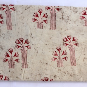 May include: White fabric with a red floral pattern. The fabric has a textured, slightly rough surface. The flowers are stylized and resemble a type of plant.