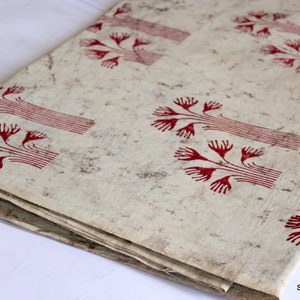 May include: A folded piece of fabric with a white background and a red tree pattern. The fabric is folded in half and the pattern is visible on both sides.