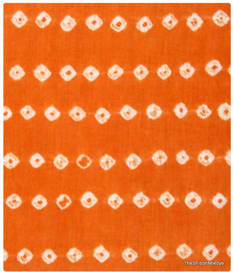May include: Orange fabric with a white tie-dye pattern of small squares. The fabric has a subtle texture.