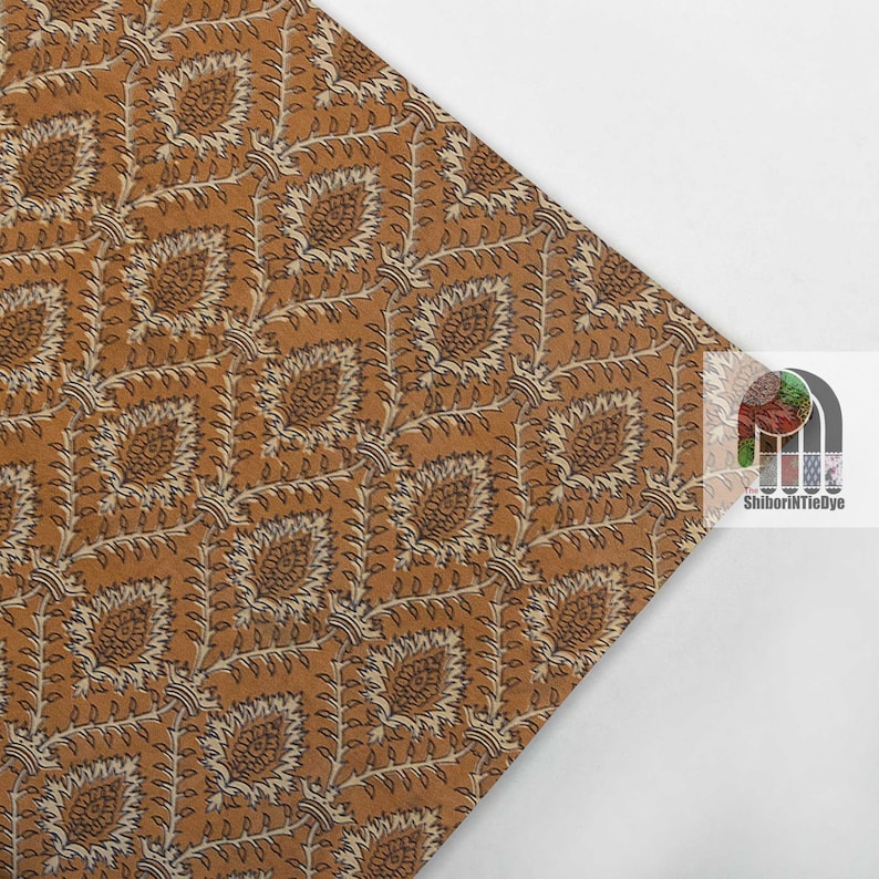 May include: A brown fabric with a white and black floral pattern. The fabric has a repeating pattern of small leaves and flowers.