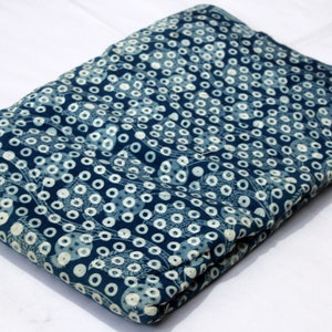 May include: A folded blue fabric with a white polka dot pattern. The fabric has a subtle floral design.